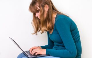 Woman working off laptop on her lap. Benefits of good posture. Propel Physiotherapy postural dysfunction treatment.