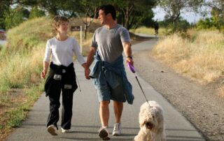 Couple walking their dog on a trail. Benefits of walking Propel Physiotherapy