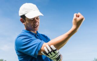 Man wincing in pain from golfer's elbow. Elbow pain treatment at Propel Physiotherapy.