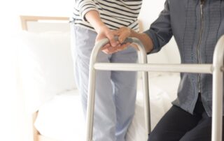 Elderly woman using walker to stand up from edge of bed. Chronic stroke rehabilitation client case study at Propel Physiotherapy.