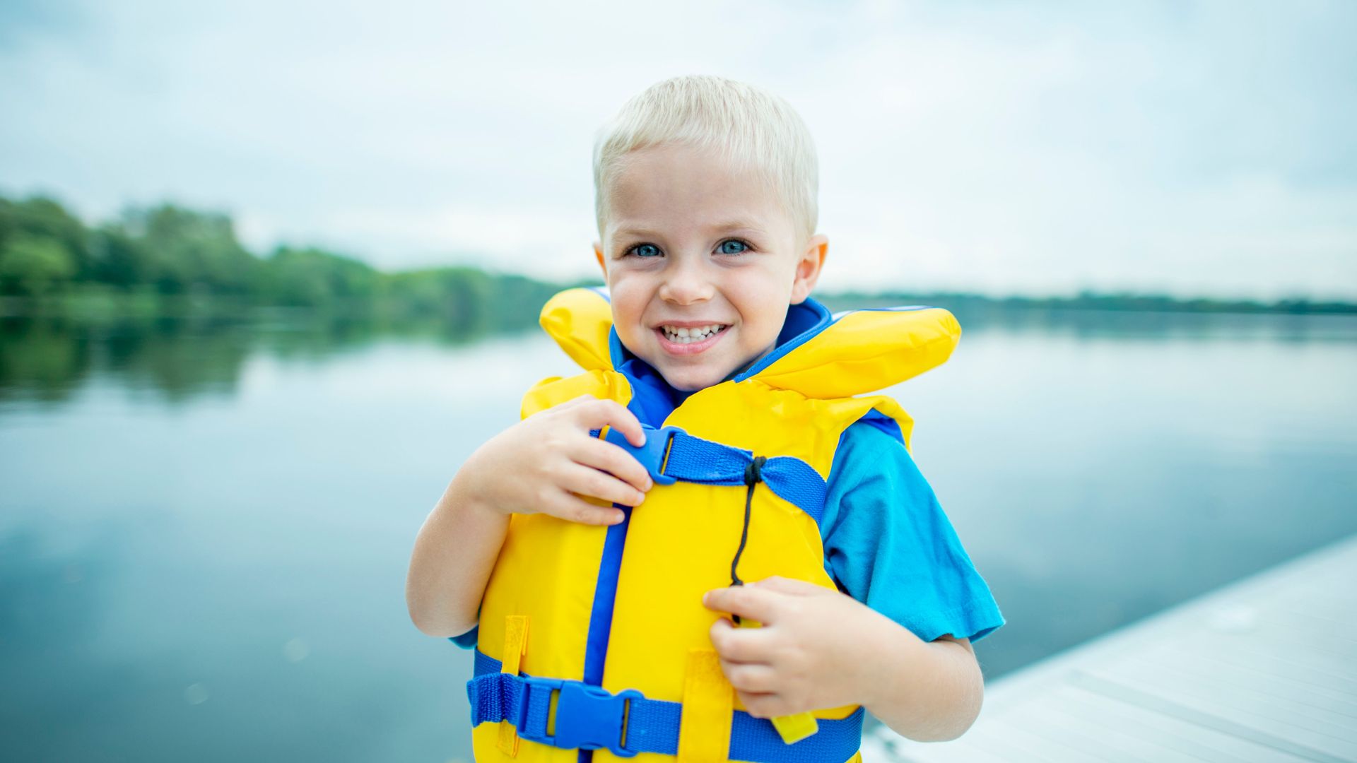 Little boy in personal floatation device by the lake. Summer safety tips for kids from Propel Physiotherapy.