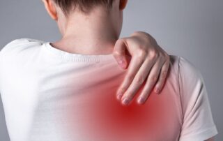 Woman holding upper back in pain. Myofascial trigger points and back pain. Propel Physiotherapy.