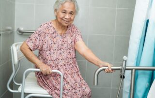 Elderly woman using grab bars and shower seat to safely use shower. Home assessment and modification services for fall prevention Propel Physiotherapy.