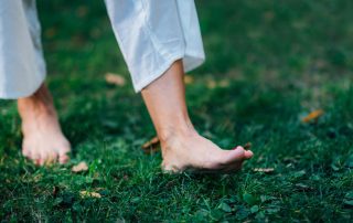 Woman walking barefoot in the grass as a grounding technique. How to enhance cognitive rehabilitation with mindfulness. Propel Physiotherapy occupational therapy and mindfulness services.