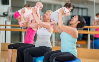 People sitting on exercise balls holding their babies up. Mommy and baby classes. Community of support for postpartum pelvic dysfunction.