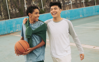 Two teen boys playing basketball at a public outdoor court. Five reasons exercise is essential for teens. Propel Physiotherapy.