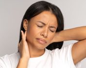 Woman holding the side of her neck with one hand and the back of neck with other hand while wincing in pain. Fibromyalgia treatment includes physiotherapy at Propel Physiotherapy.