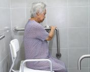 Elderly woman sitting in her modified showers with grab bars and shower chair. Strategies for healthy aging in place. Propel Physiotherapy.