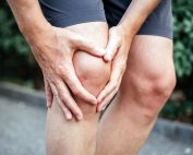 Man in shorts out for a run holding his knee in pain. Meniscus injury treatment Propel Physiotherapy.