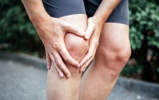 Man in shorts out for a run holding his knee in pain. Meniscus injury treatment Propel Physiotherapy.