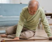 Elderly man with cane on the floor next to his couch after a fall in the living room of his home. Safe techniques for how to get up from the floor after a fall. Propel Physiotherapy.