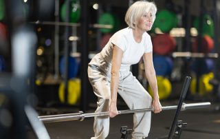 Older woman doing a deadlift exercise at the gym. How resistance training reduces risk of osteoporosis fractures. Propel Physiotherapy healthy aging.