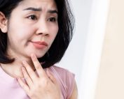 Woman with facial palsy touches face while looking pensive. Facial palsy treatment at Propel Physiotherapy.