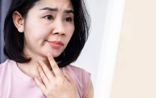 Woman with facial palsy touches face while looking pensive. Facial palsy treatment at Propel Physiotherapy.