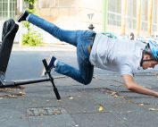 Young man wearing helmet falling off e-scooter onto stone walkway. E-scooter injury prevention tips from Propel Physiotherapy.